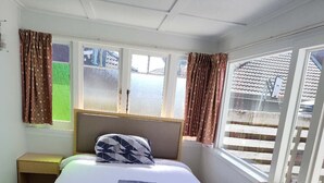 Een hotelkamer met een bed, nachtkastje, raam met gordijnen en een bank.