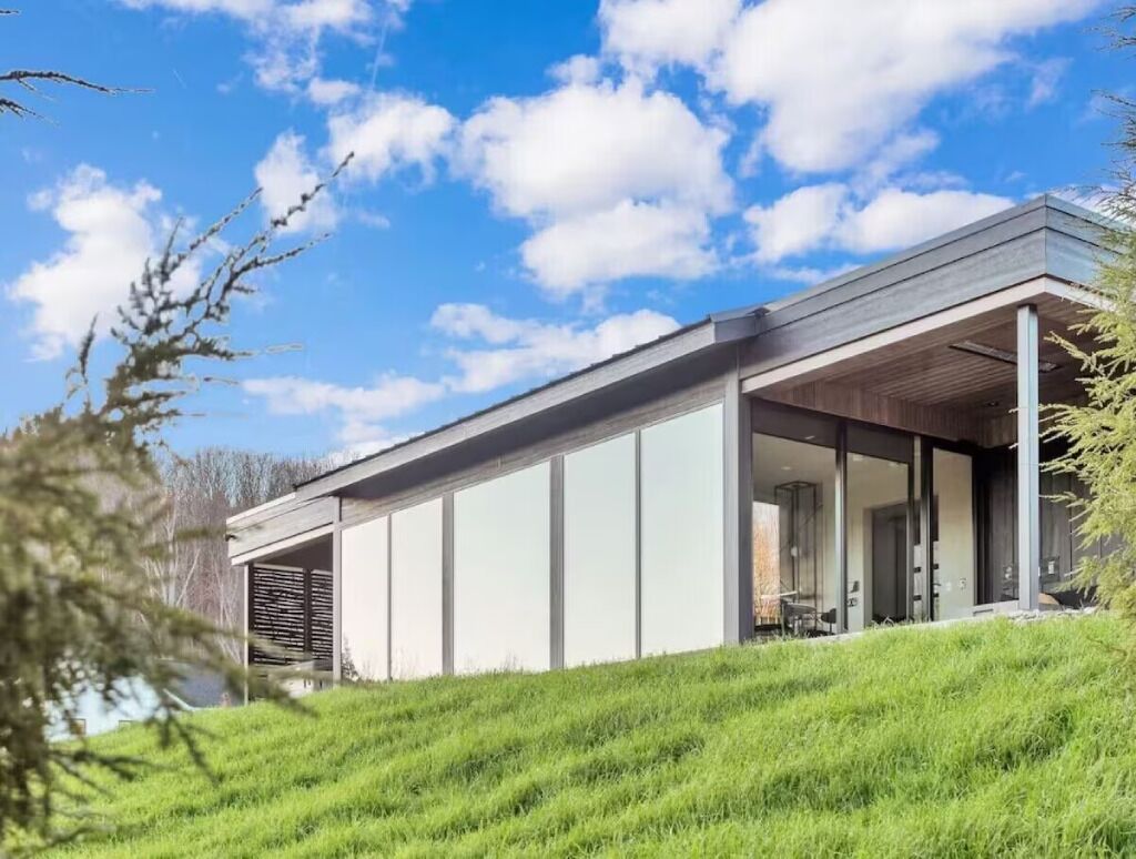 Een modern huis met een plat dak, grote ramen en een overdekte veranda.