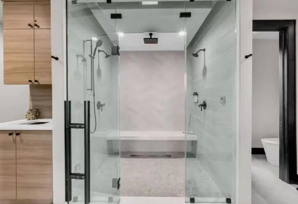 A modern bathroom with a glass enclosure, a white sink, and a toilet.
