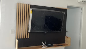 Una sala de estar moderna con un televisor de pantalla plana grande montado en un panel de madera.