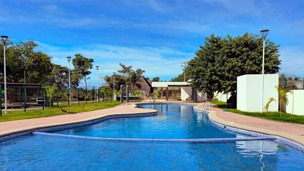 Una piscina de borde curvo, rodeada por un sendero empedrado y vegetación.