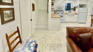 Une cuisine moderne avec des meubles blancs, un îlot central et un réfrigérateur.
