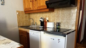 Une cuisine compacte dotée de meubles en bois, d’un lave-vaisselle, d’un grille-pain et d’une machine à café.