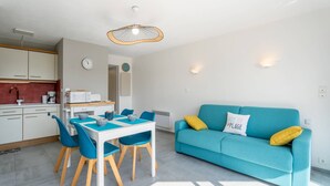 Une cuisine moderne avec des meubles blancs et un coin repas comprenant une table et des chaises bleues.