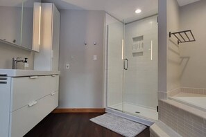 Un bany modern amb un cubicle de dutxa de vidre, un lavabo encastrat i un suport per a tovalloles.