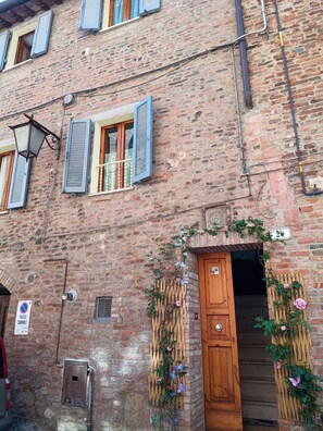 A brick building with a wooden door, a 'Passe Carriere' sign, and a '2' address sign.