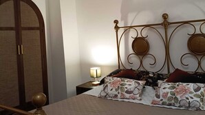 Ein Schlafzimmer mit Bett, Nachttisch, Lampe, Kleiderschrank und Deckenleuchte.