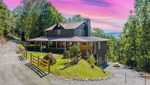 A two-story house with a porch, a covered patio, and a gravel driveway. - PRIVATE! 2 Miles To PF! Charming 4BR Farmhouse w/Hot Tub, PT, Fire Pit & VIEWS! (Sevierville)