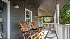 A covered porch with wooden rocking chairs and a wooden bench. - PRIVATE! 2 Miles To PF! Charming 4BR Farmhouse w/Hot Tub, PT, Fire Pit & VIEWS! (Sevierville)