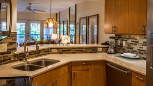 A modern kitchen with granite countertops, wooden cabinets, and a backsplash of mosaic tiles. - Most Beautiful View on Key West? (Key West)