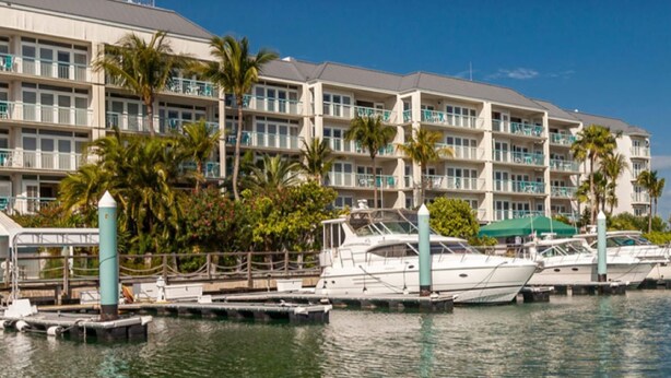 A marina with several boats docked, a hotel with multiple balconies, and palm trees. - Most Beautiful View on Key West? (Key West)