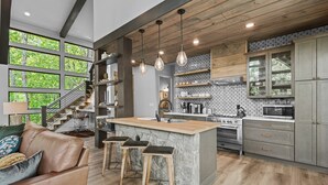 Una cocina moderna con una isla central, vigas de madera y una pared de acento de piedra.