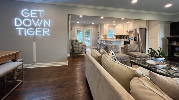 A modern living room with a sofa, a coffee table, and a neon sign reading "GET DOWN TIGER". - Stylish 3BR in Garden District near parks, river views, Neville High, and ULM. (Monroe)