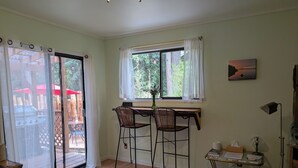 A room with a bed, a desk with two chairs, a window with curtains, a painting on the wall, and a lamp. - Island paradise with private hot tub -- pet friendly & breakfast included! (Pender Island)