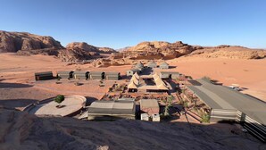 A desert resort with multiple tents and buildings, arranged in a semi-circular layout with a clear view of the surrounding rocky landscape. - Room-wadi RUM Guide, Camp & Tour (Wadi Rum)