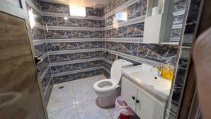 A bathroom with a toilet, sink, and marble-patterned walls. - Room-wadi RUM Guide, Camp & Tour (Wadi Rum)
