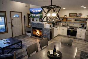 A modern living room with a fireplace, dining area, kitchen, and a TV mounted on the wall. - 3BR Dog Friendly Townhome between Ski Resort and Downtown (Durango)
