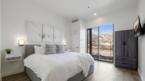 A modern bedroom with a large bed, bedside tables, a wardrobe, and a view of a snowy landscape through the glass door. - Luxury 1BR Condo at The Mason, AC, Jordanelle, Pool & Hot Tub Access (Heber City)