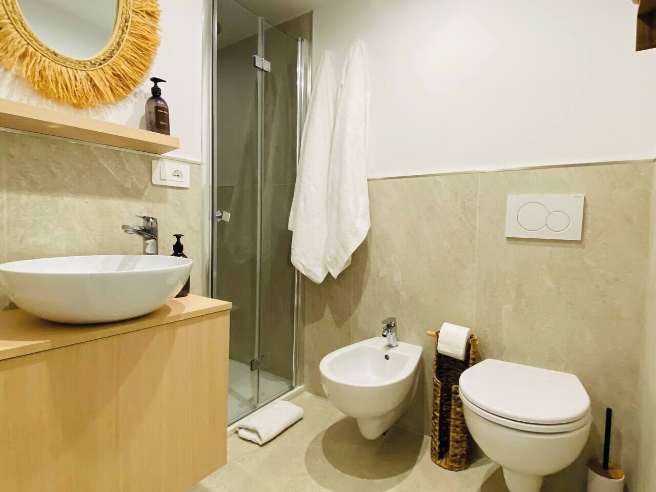 Un bany amb un rentapeus, bidet i vàter blancs.