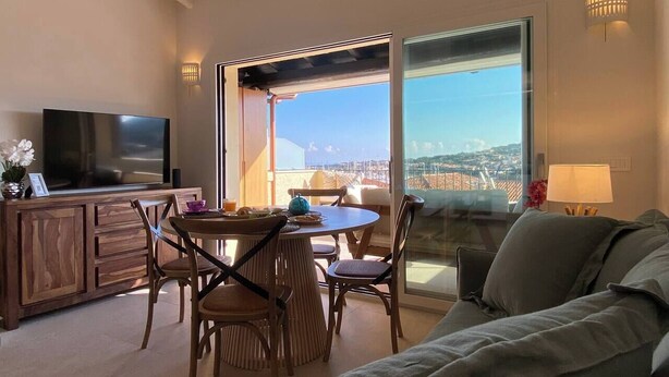 Een woonkamer met een televisie, een eettafel, stoelen en een bank.