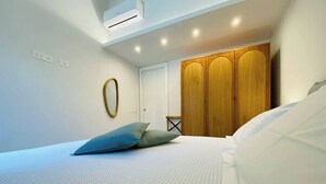 Een slaapkamer met een bed, een kledingkast en een wandairconditioner.