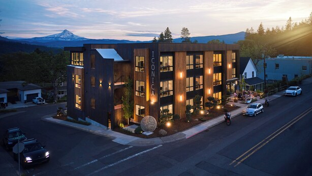 A modern building with a prominent 'ICONICA' sign, featuring a multi-story structure with large windows and a landscaped front yard with a spherical sculpture. - Penthouse studio suite, downtown White Salmon, suite 15 (White Salmon)