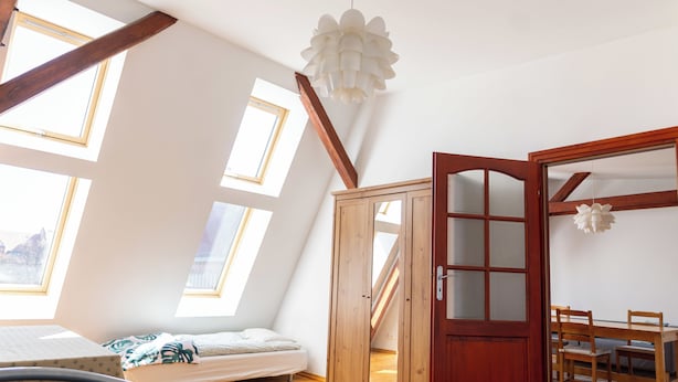 Een kamer met een stapelbed, een houten kast, een eettafel met stoelen en een groot raam met uitzicht op een berg.