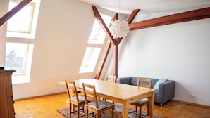 Een eetgedeelte met een houten tafel en stoelen, een bank en een kamerkleed met dessin.