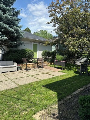 Un jardin à l’arrière d’une maison, comprenant une terrasse, du mobilier d’extérieur et une pelouse.