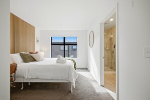 A modern bedroom with a bed, bedside table, and a window with a view.