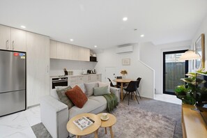 A compact living space with a kitchenette, a dining area, and a seating area with a sofa and coffee table.