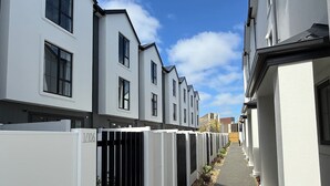 Een rij moderne, witte gebouwen met identiek architectuur, een smal pad en een heldere lucht.