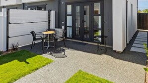 Een modern huis met twee verdiepingen en een patio met een tafel en stoelen.