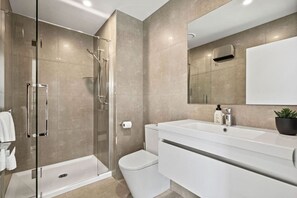 Un bagno moderno con doccia vetro, WC bianco e mobile lavabo con specchio.