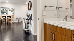 A modern bathroom with wooden cabinets, a white sink, and a large mirror. - Trailside Charm | TART Trail | Downtown | (Traverse City)