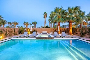 Une piscine avec des chaises longues et des palmiers.