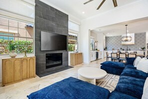 A modern living room with a fireplace, a flat-screen TV, and a blue sofa.