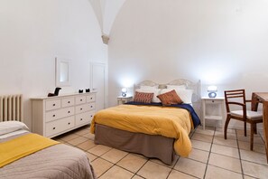 A bedroom with a bed, bedside tables, a chair, a dresser, and a radiator. - Xenia Old Town | Lecce Selection (Lecce)