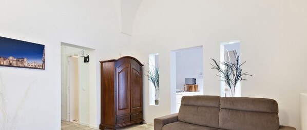 A living room with a sofa, a wooden cabinet, and a framed picture on the wall. - Xenia Old Town | Lecce Selection (Lecce)