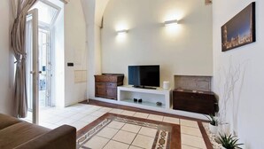 Una sala de estar con televisor, aparador de madera y alfombra estampada.