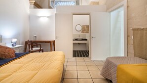Un dormitorio con dos camas, un escritorio y un baño pequeño.