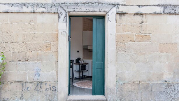 A doorway leading into a room with a small table and a chair. - Obelisk Studio - Lecce Selection (Lecce)