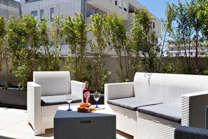 A patio area with outdoor seating, a bottle of wine, and a glass of wine on a table. - Renoir Apartment & Parking - Lecce Selection (Lecce)