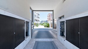 A corridor leading to a balcony with a view of other buildings.
