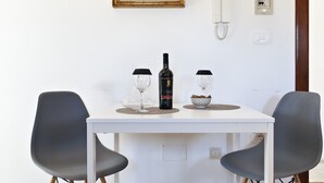 A dining table with two chairs, a bottle of wine, two wine glasses, and a bowl of cookies.