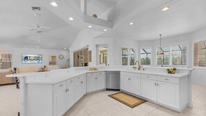 Una cocina amplia con muebles blancos, lavavajillas y una isla grande.