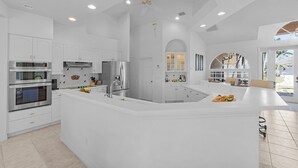 Una cocina moderna con armarios blancos, electrodomésticos de acero inoxidable y una isla central.