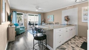 Una cocina moderna con gabinetes blancos, encimera de granito y un taburete de bar.