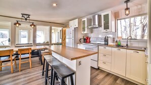 A modern kitchen with wooden countertops, white cabinets, and a central island with stools.