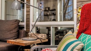 A cozy living area with a wooden table, a grey desk lamp, a grey sofa, and a red throw blanket.